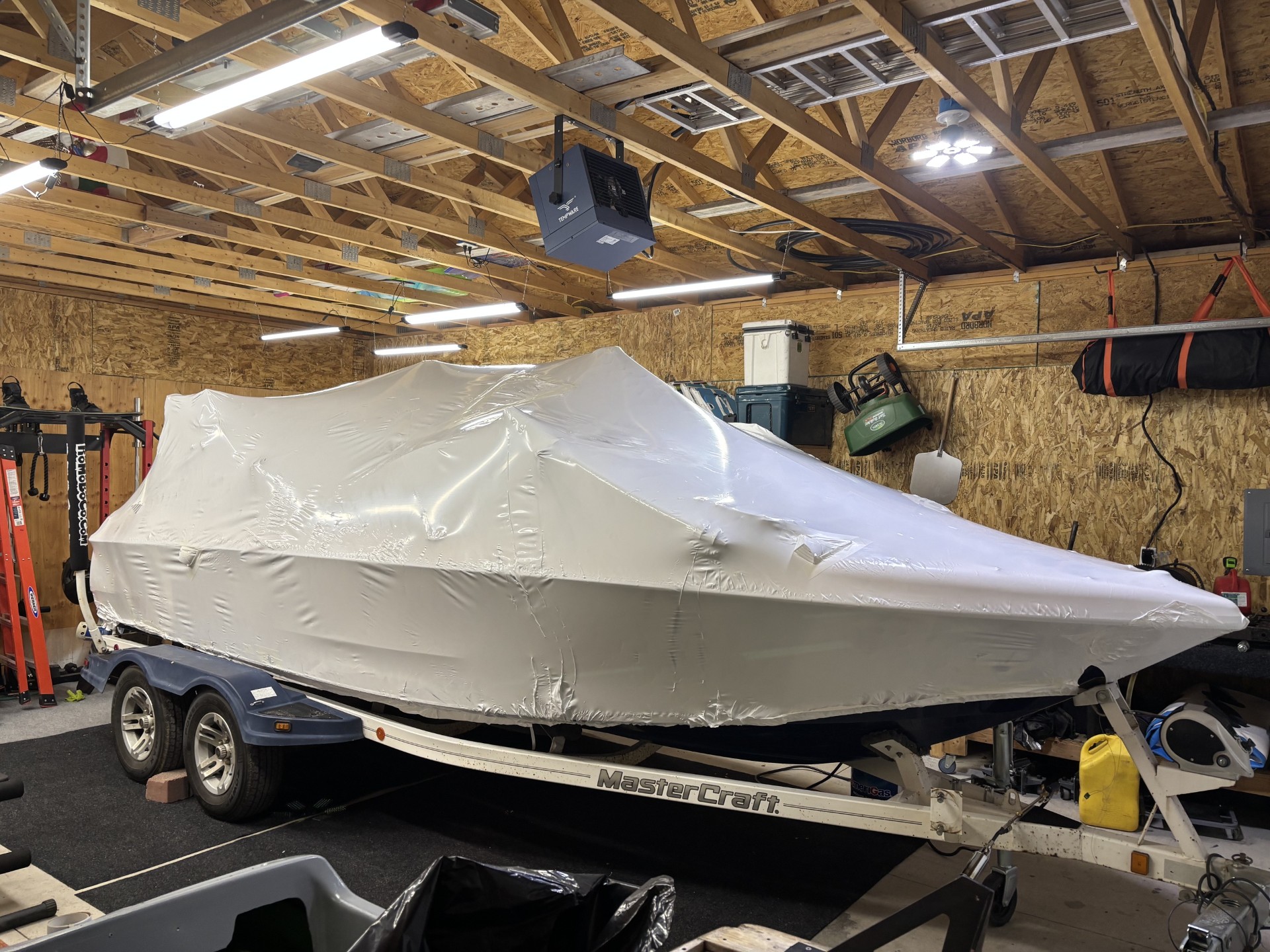 MasterCraft boat covered in white shrink wrap on its trailer inside a workshop